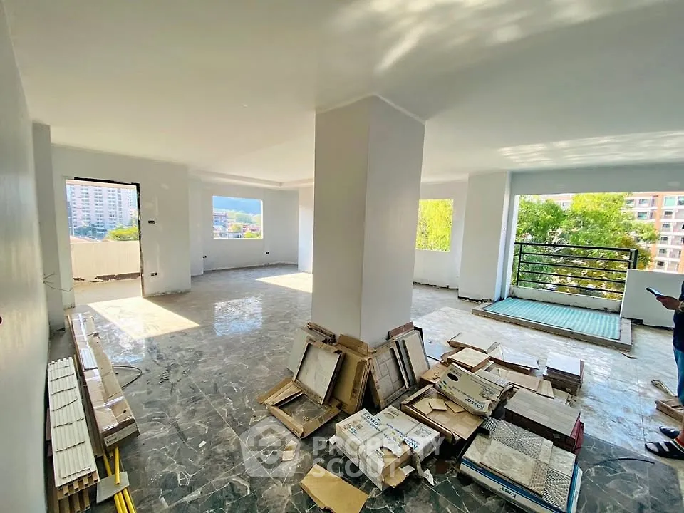Spacious open-plan living area with large windows and balcony access, ideal for modern living.