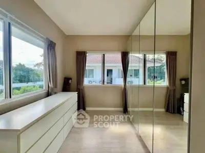 Spacious bedroom with mirrored closet and scenic window view in modern home.