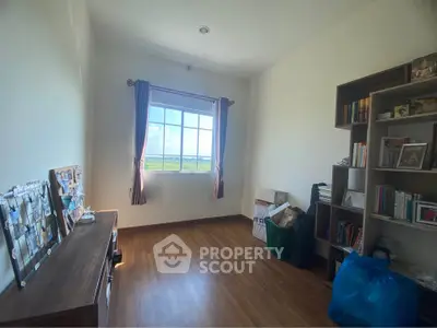 Bright study room with wooden flooring and large window offering scenic views, perfect for a home office setup.
