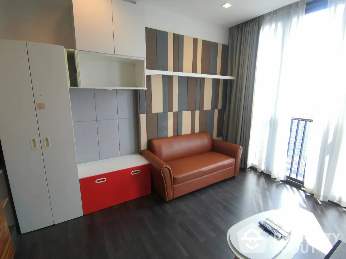 Modern living room with sleek furniture and vibrant accent wall, bathed in natural light from floor-to-ceiling window, perfect for urban living.