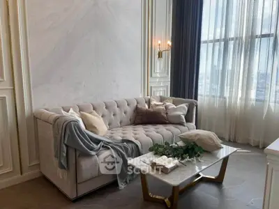 Luxurious living room with elegant sofa and marble accents, featuring large windows and stylish decor.