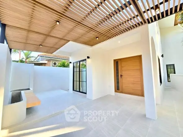 Modern exterior with wooden pergola and sleek entrance in a sunny setting.