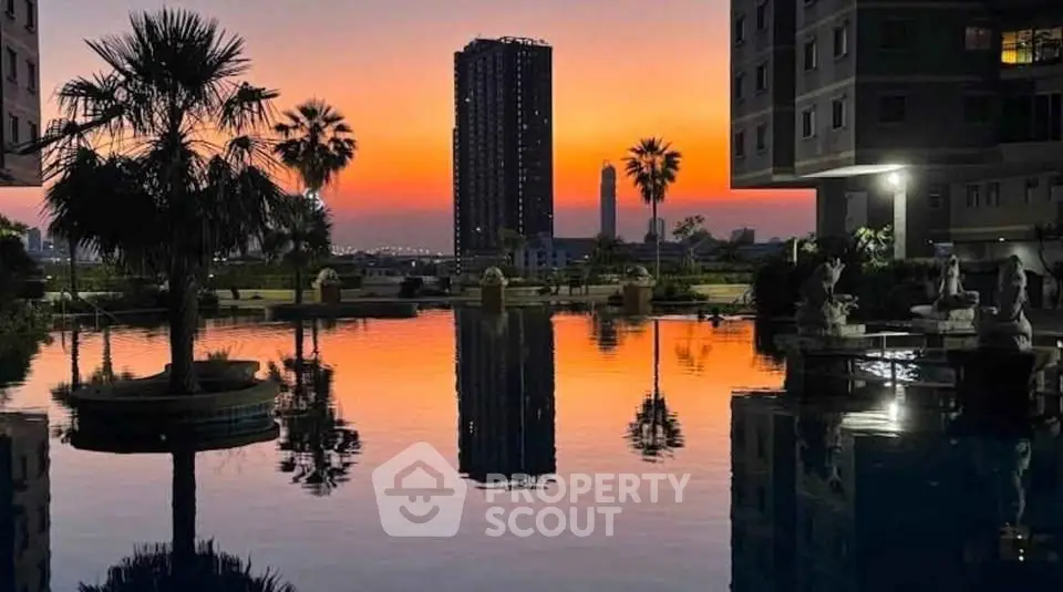 Stunning sunset view over a luxurious residential pool with palm trees and high-rise buildings.
