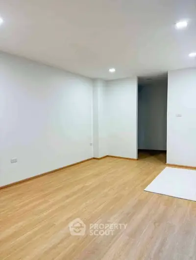 Spacious empty room with wooden flooring and recessed lighting, ideal for customization.
