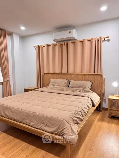 Cozy bedroom with wooden bed frame, neutral decor, and air conditioning, perfect for relaxation.
