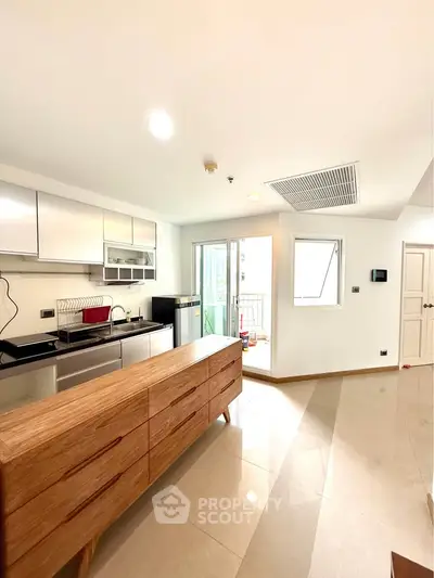 Modern kitchen with sleek cabinetry and open layout leading to a bright balcony.