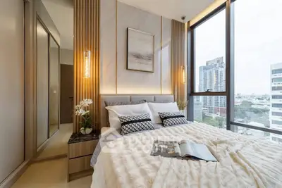 Luxurious bedroom with floor-to-ceiling windows offering stunning city views, elegant decor, and cozy bedding.