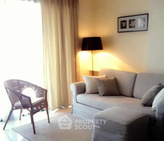 Cozy living room with soft lighting, beige sofa, wicker chair, and elegant decor.