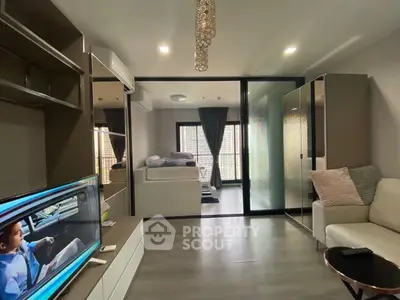 Modern living room with sleek design and glass partition leading to bedroom, featuring stylish decor and natural light.
