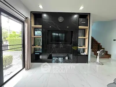 Modern living room with sleek black marble TV wall and large windows