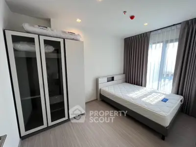 Modern bedroom with large window and stylish wardrobe in a bright apartment.