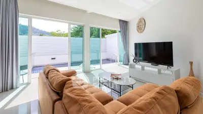 Spacious living room with modern decor and pool view, featuring large windows and cozy seating.