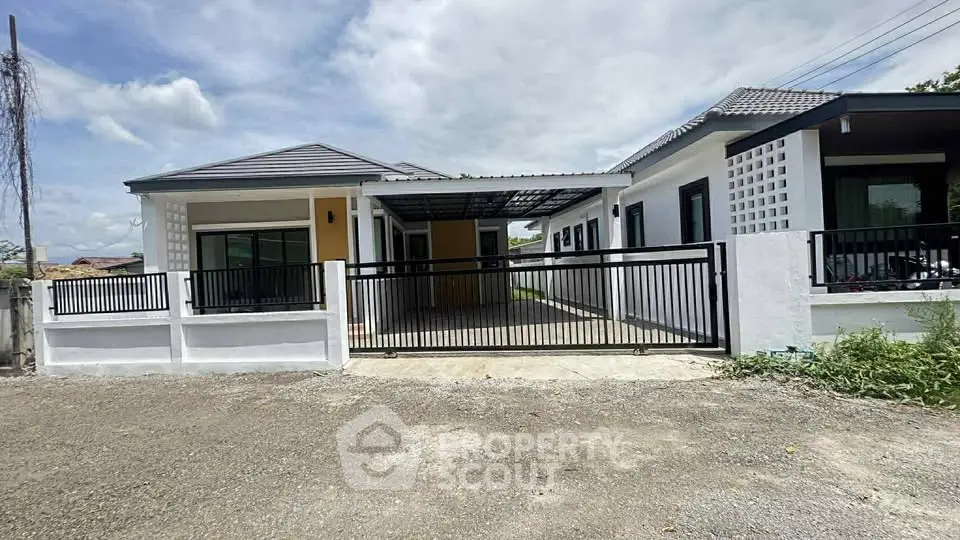 Modern single-story house with gated driveway and contemporary design.