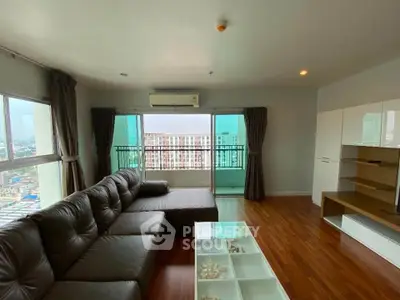 Spacious living room with modern furniture and city view balcony in high-rise apartment.