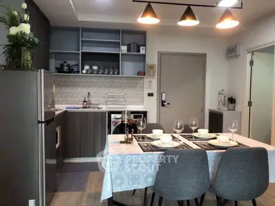 Modern kitchen with dining area, featuring sleek cabinetry and elegant table setting.