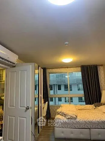 Cozy bedroom with modern decor and large window offering natural light.