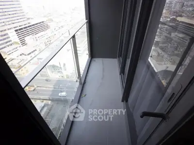 Modern high-rise balcony with glass railing offering cityscape views.