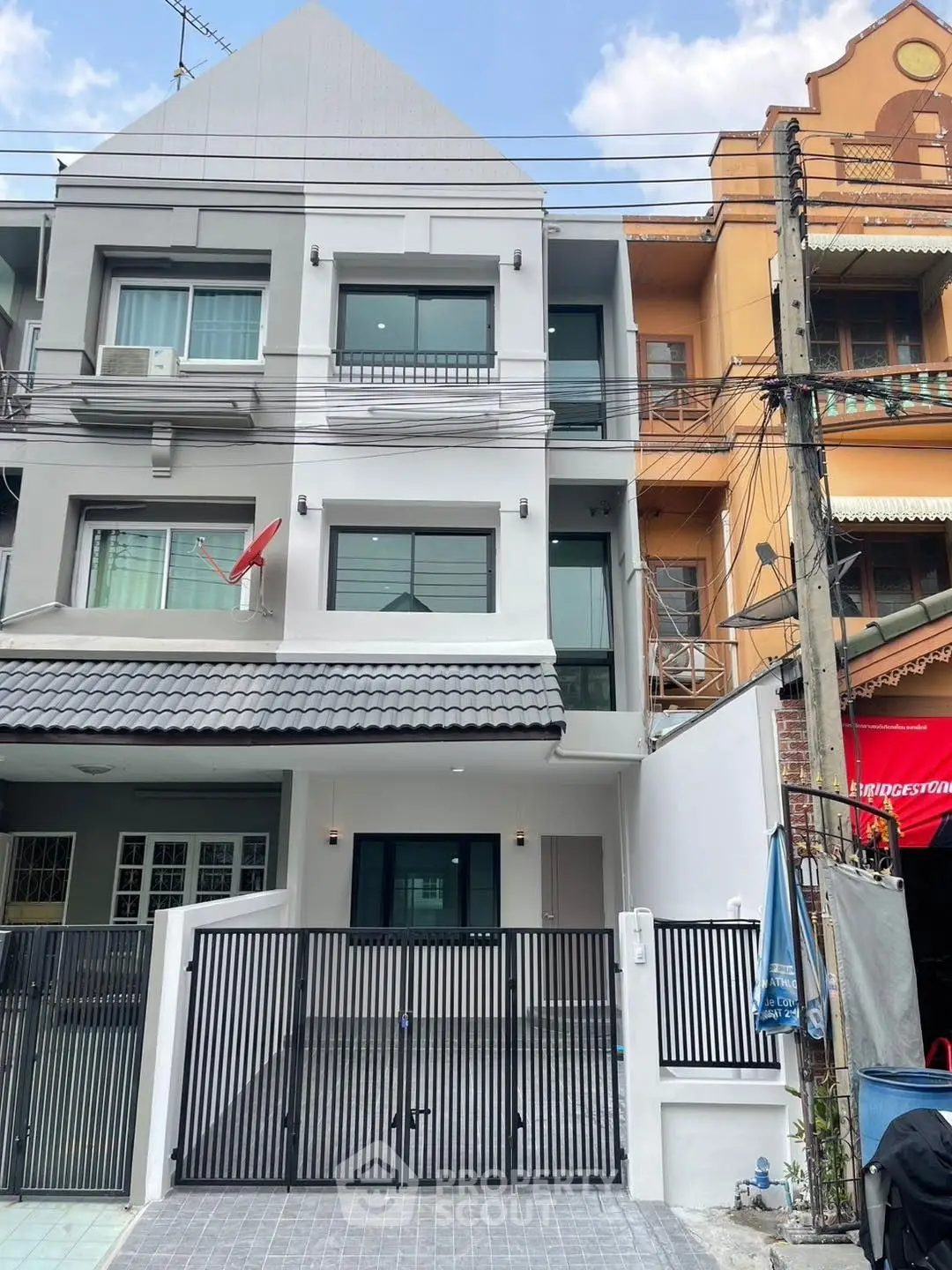 Modern three-story townhouse with gated entrance and contemporary facade.