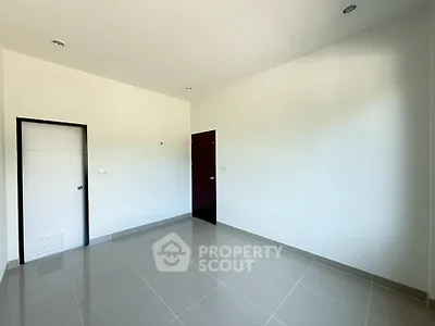 Spacious empty room with glossy tiled floor and white walls, ready for customization.