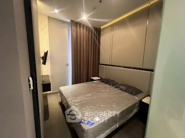 Modern bedroom with sleek design and ambient lighting, featuring a comfortable bed and wall-mounted TV.