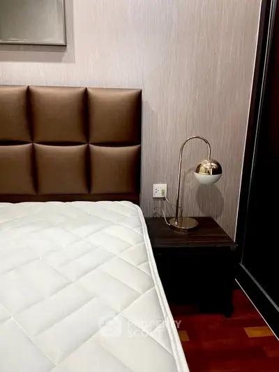 Modern bedroom with stylish headboard and sleek bedside lamp.