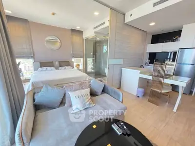 Modern studio apartment with stylish decor and open layout, featuring a cozy bed, chic sofa, and sleek kitchen area.