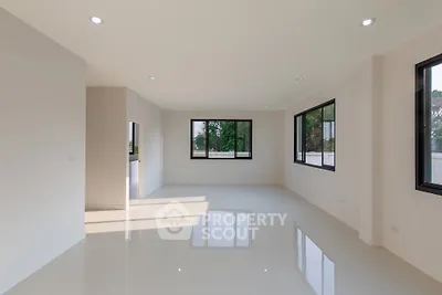 Spacious modern living room with large windows and glossy floors, offering abundant natural light and serene views.