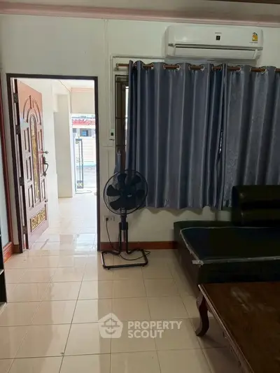 Cozy living room with air conditioning and elegant curtains, featuring a stylish wooden door and tiled flooring.