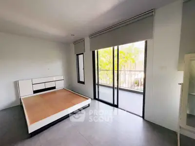 Spacious bedroom with large windows and balcony access, offering natural light and outdoor views.