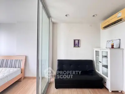 Modern apartment interior with glass partition, black sofa, and air conditioning unit.