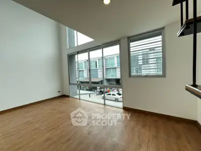 Spacious modern living room with large windows and wooden flooring, offering a bright and airy atmosphere.