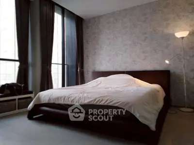 Spacious bedroom with modern decor and large windows offering natural light.