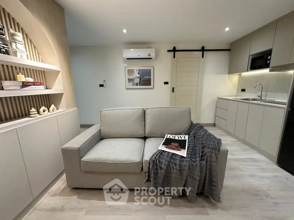 Modern living room with sleek kitchen, cozy sofa, and stylish decor in open layout apartment.