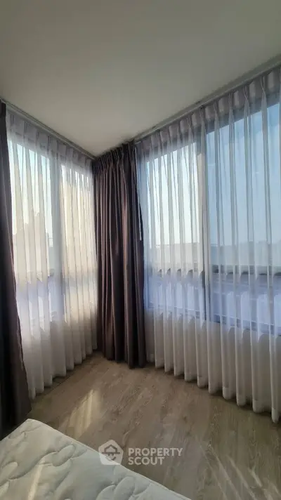 Bright corner bedroom with floor-to-ceiling windows and sheer curtains