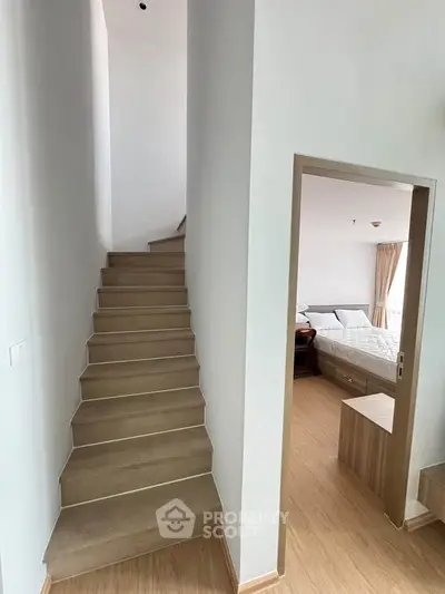 Modern interior with wooden staircase leading to a bright bedroom with natural light.