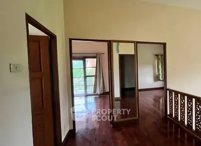 Spacious interior with wooden flooring and large windows offering natural light.