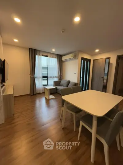 Modern living room with wooden flooring, cozy sofa, and dining area in open layout apartment.