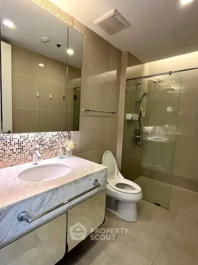 Modern bathroom with glass shower and marble sink in luxury apartment