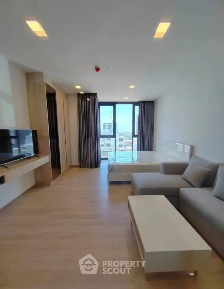 Modern living room with city view, featuring sleek furniture and large windows.