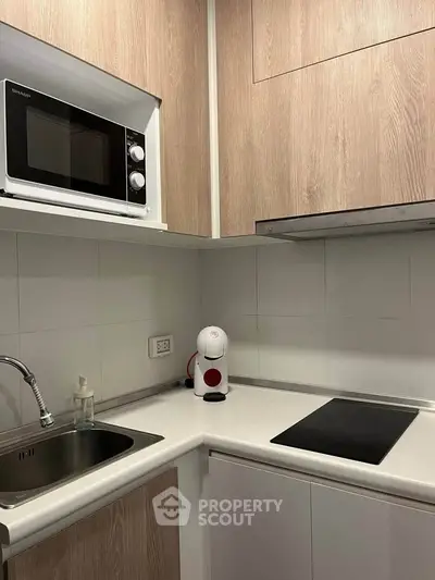 Modern compact kitchen with sleek appliances and wooden cabinetry