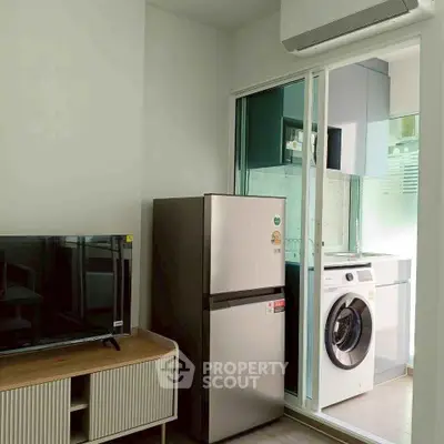 Modern apartment interior with sleek kitchen appliances and stylish TV setup.