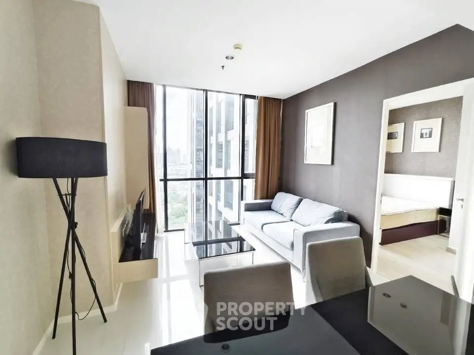 Modern living room with large windows and stylish furniture in a high-rise apartment.