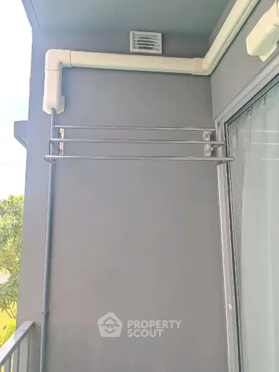 Modern balcony with sleek metal railing and gray walls, perfect for urban living.