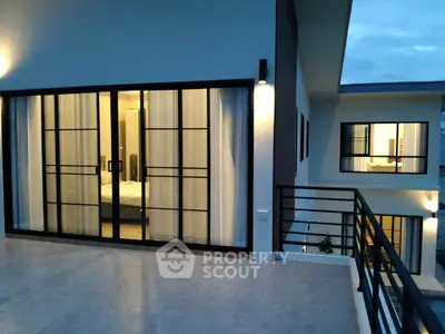 Modern luxury home with large glass doors and spacious balcony at dusk.
