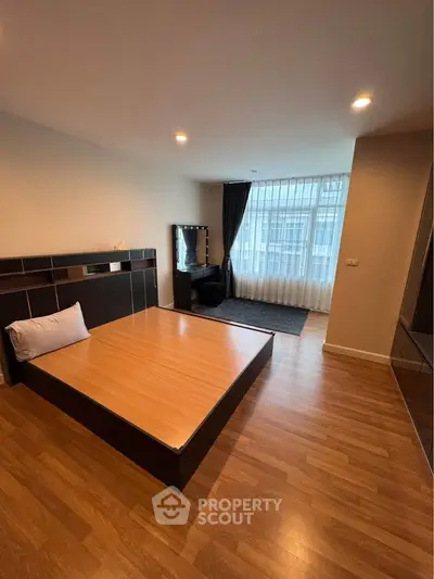 Spacious bedroom with modern design and large window for natural light.