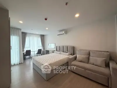 Modern bedroom with stylish decor, featuring a comfortable bed, cozy sofa, and a bright window view.