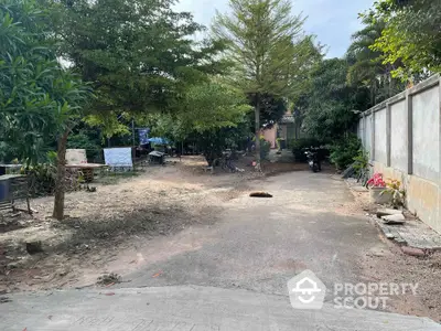 Spacious outdoor area with trees and paved driveway in residential property