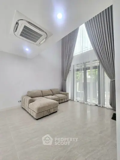 Spacious modern living room with high ceilings and elegant curtains