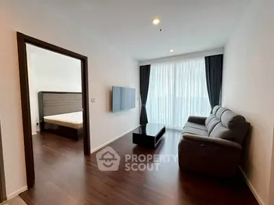 Modern living room with sleek furniture and natural light, adjacent to a cozy bedroom.