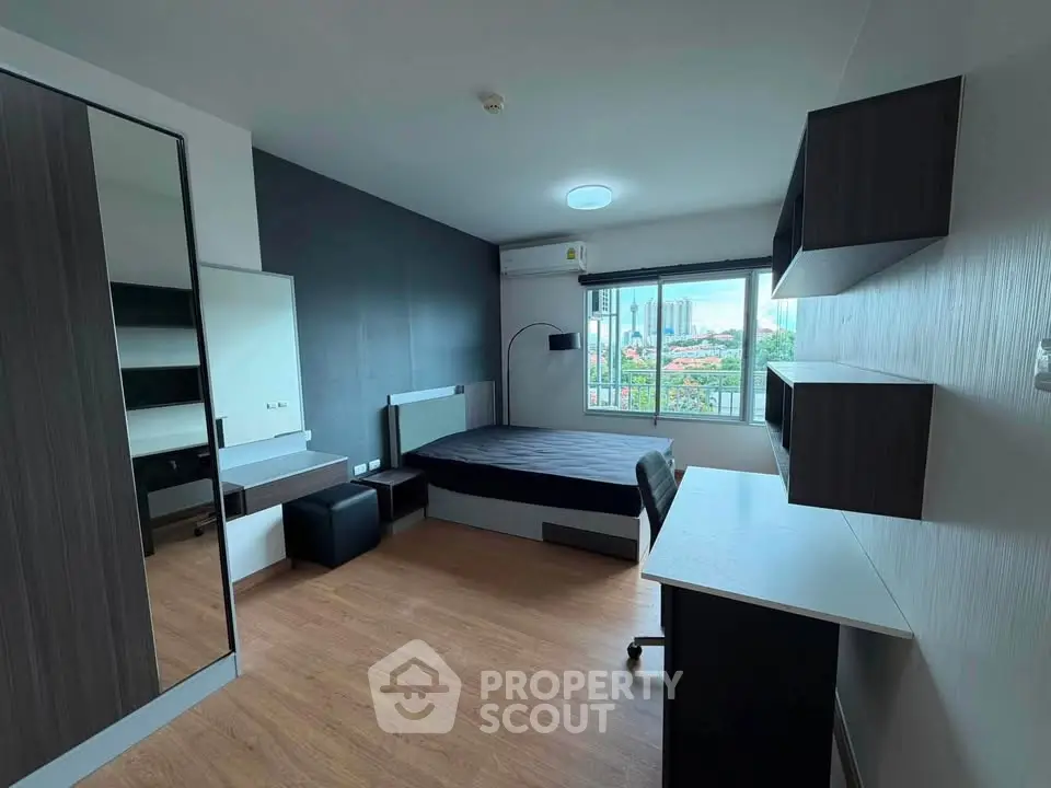 Modern bedroom with city view, featuring sleek furniture and ample natural light.